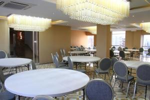 a dining room with tables and chairs and chandeliers at Blossom Hotel Dhaka in Dhaka