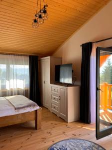 a bedroom with a bed and a flat screen tv at Chalet Marilyn in Topliţa
