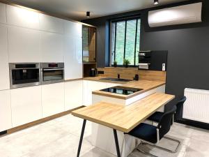 a kitchen with white cabinets and a wooden table at Platinum Apartment in Wałbrzych +5 photos