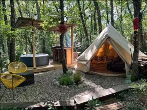 a tent in the woods with a hot tub at Tente en jardin in Boulazac