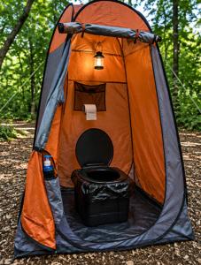 an orange and black tent with a toilet in it at Tente en jardin in Boulazac