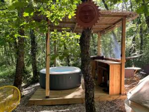 a hot tub on a wooden deck under a tree at Tente en jardin in Boulazac