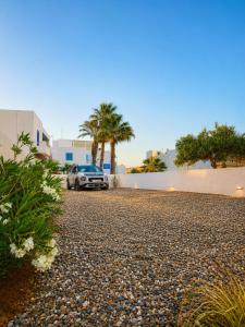 a car parked on a gravel driveway with palm trees at DelMar Suites Syros in Finikas
