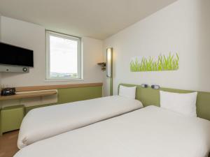 a bedroom with two beds and a tv at ibis budget Bern Expo in Bern +59 photos