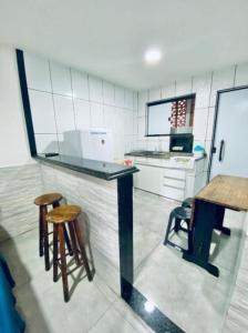 a kitchen with a counter with two stools and a table at Nossa Casa Arraial LOFT in Arraial do Cabo