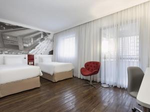 a hotel room with two beds and a red chair at Mercure Sao Paulo Paulista in São Paulo +88 photos