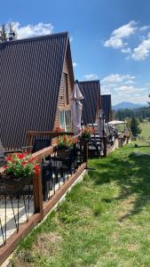 a row of tables and chairs with flowers and an umbrella at WoodMood in Žabljak