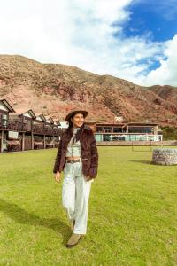a woman standing in the grass in a field at RUSTICA HOTELES CUSCO Urubamba in Urubamba