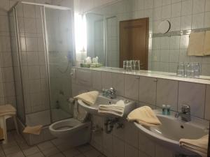 a bathroom with a sink and a toilet and a mirror at Hotel Zur Buche in Bockhorn