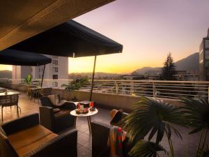 a rooftop patio with chairs and tables and an umbrella at Novotel Santiago Vitacura in Santiago