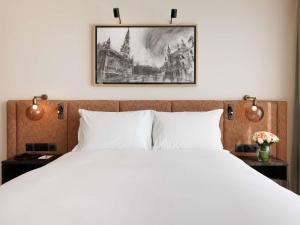 a bedroom with a white bed and a painting on the wall at Sofitel Brussels Europe in Brussels +196 photos