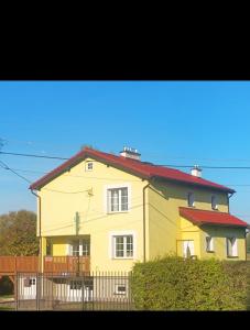 a yellow house with a red roof at Dom Na Fali in Pasym