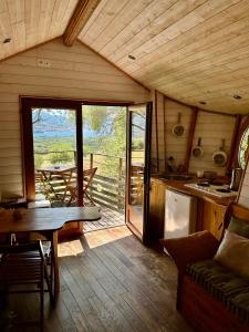 a living room with a table and a kitchen with a view at Cabane Dans les Arbres, Domaine de l Ogliastru in Olmeto