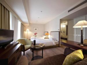 a hotel room with a bed and a television at The Cypress Mercure Hotel Nagoya in Nagoya