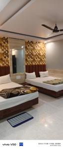 a room with two beds and a flat screen tv at Shree radhe palace in Datia