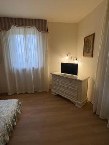 a bedroom with a television on a dresser with a window at Le Magnolie 1924 in Casciana Terme