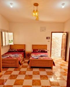 a bedroom with two beds and a checkered floor at شاليه العميد chalet in Marsa Matruh
