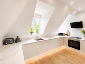 a kitchen with white cabinets and a sink at Barnet Luxe 2 Bedroom Penthouse in Barnet