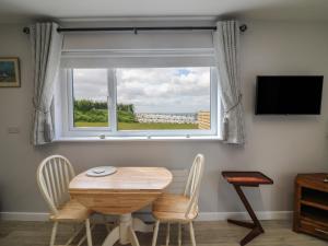 a table and chairs in a room with a window at Radharc an Hook Estuary Bliss in Duncannon