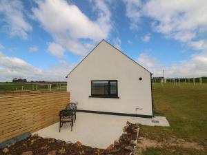 a small white house with a chair in a field at Radharc an Hook Estuary Bliss in Duncannon