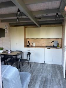 a kitchen with white cabinets and a table and chairs at Domki Na Skraju in Stegna +5 photos