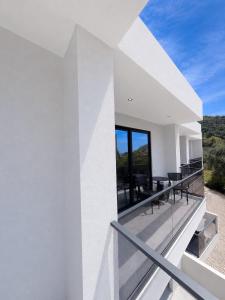 a white house with a balcony with tables and chairs at Palms Guest House in Himare