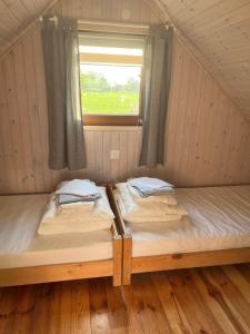 two beds in a small room with a window at Domki Na Skraju in Stegna