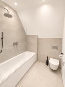 a white bathroom with a tub and a toilet at Barnet Luxe 2 Bedroom Penthouse in Barnet +11 photos