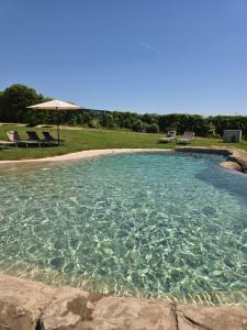 a pool of water with chairs and an umbrella at Finca SOTOMAR-casa rural Simancas in Simancas