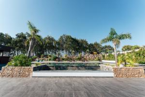 a swimming pool in a park with palm trees at Lagoa Beach House B&B - Breakfast included in Serra do Bouro