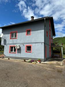 a gray house with red windows on the side of it at Apartman HUSEIN in Jajce