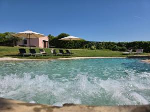 a pool of water with chairs and umbrellas at Finca SOTOMAR-casa rural Simancas in Simancas