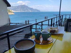 a table with two cups and a piece of cake on a balcony at Casa Reginella - Borgo Marinaro in Conca dei Marini