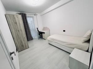 a bedroom with a bed and a desk and a window at Hij Apartaments in Rădăuţi