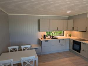 a kitchen with white cabinets and a table and a window at Oslofjord Sea View in Hvitsten