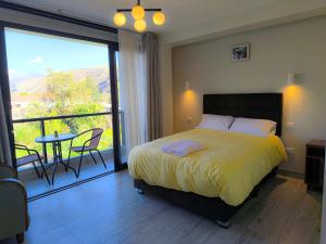a bedroom with a bed and a balcony with a table at PACHAMAMA APARTMENt, MODERNO, ACOGEDOR Y CON VISTA PANORAMICA in Urubamba