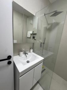 a white bathroom with a sink and a shower at Dio East Apartments in Tirana +14 photos