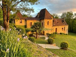 an old house with a garden in front of it at Le Manoir du Rocher in Domme
