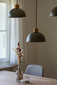 a table with two lamps and a vase with flowers at Trois Lacs Suites in Erlach