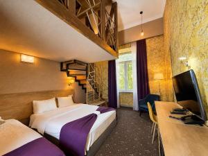 a hotel room with two beds and a tv and a desk at Hotel Gladius Inn in Tbilisi City