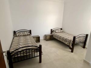 two beds in a room with white walls at Chic apartment with secure pool in Oued Laou