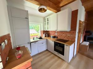 a kitchen with white cabinets and a brick wall at Gąsiorówka in Gryżyna