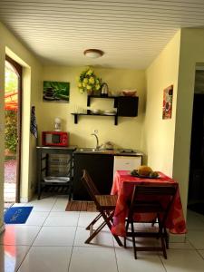 a kitchen with a table with a red table cloth on it at Le Touloulou , vue mer et jardin tropical in Le Lorrain