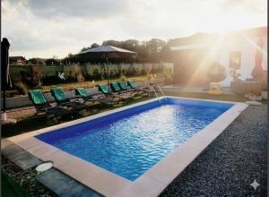 a swimming pool with chairs and an umbrella at Green Nest in Laktaši