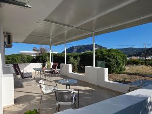 a patio with tables and chairs and a view of mountains at Kos Harmony Apartments in Kefalos