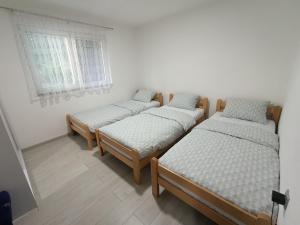 three twin beds in a room with a window at Apartman HUSEIN in Jajce