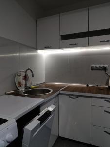 a kitchen with white cabinets and a sink at Apartman HUSEIN in Jajce +6 photos