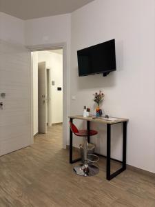 ein Zimmer mit einem Schreibtisch und einem Fernseher an der Wand in der Unterkunft Capizzi Rooms in Bronte