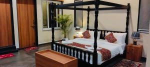 a bedroom with a black canopy bed with red pillows at Wildexoticventure in Seonī