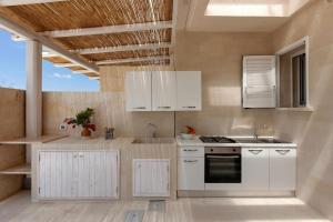 a kitchen with white cabinets and a stove at Villa La Rimunda in Otranto
